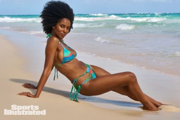 Drew Dorsey poses on the sand in a green and blue string bikini.